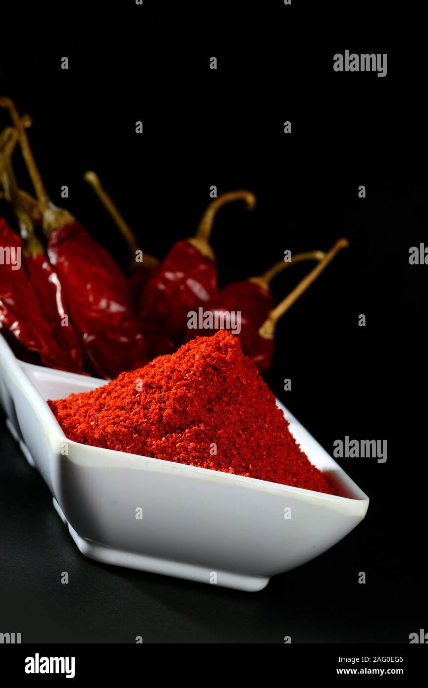 chilly powder with red chilly in white plate, dried chillies on black ...