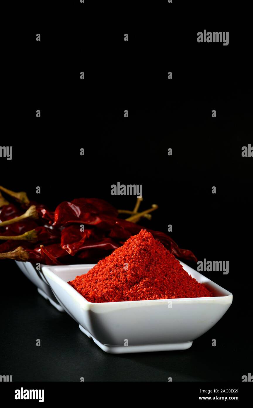 chilly powder with red chilly in white plate, dried chillies on black ...