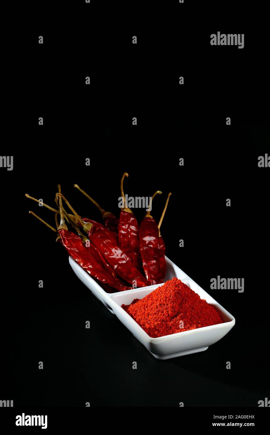 chilly powder with red chilly in white plate, dried chillies on black ...