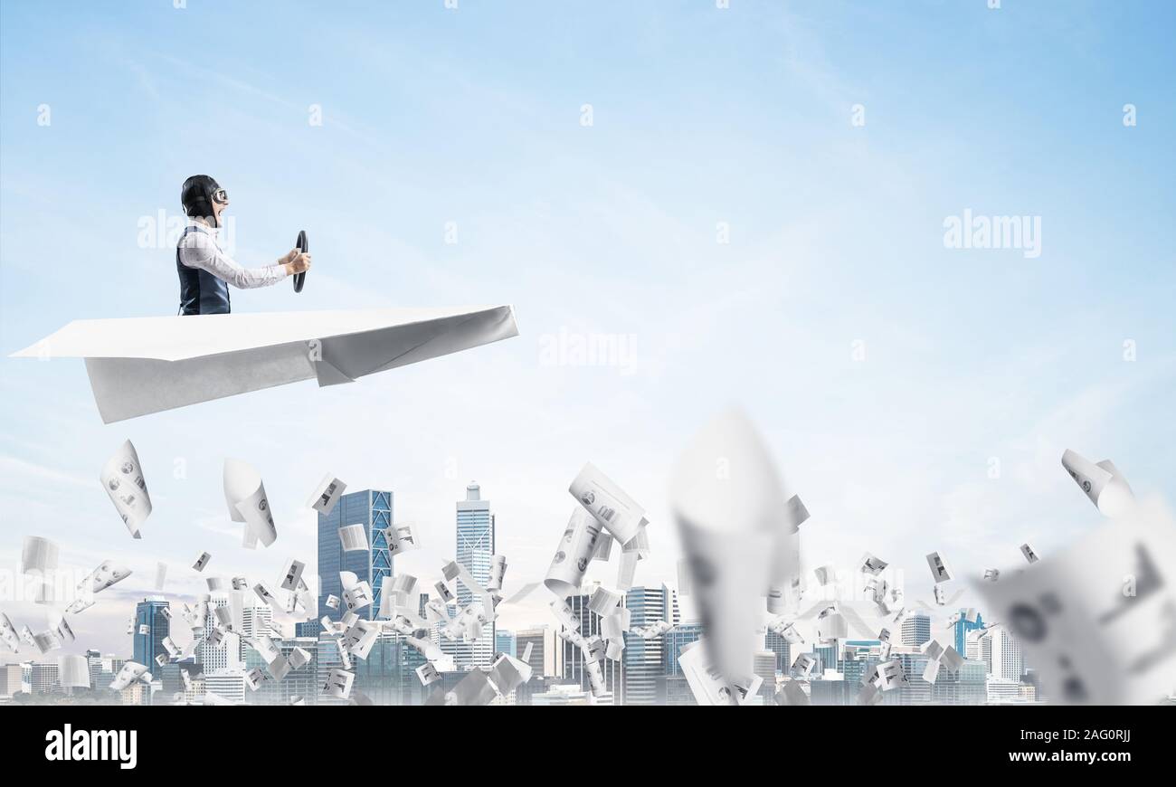 Aviator driving paper plane above business center Stock Photo - Alamy