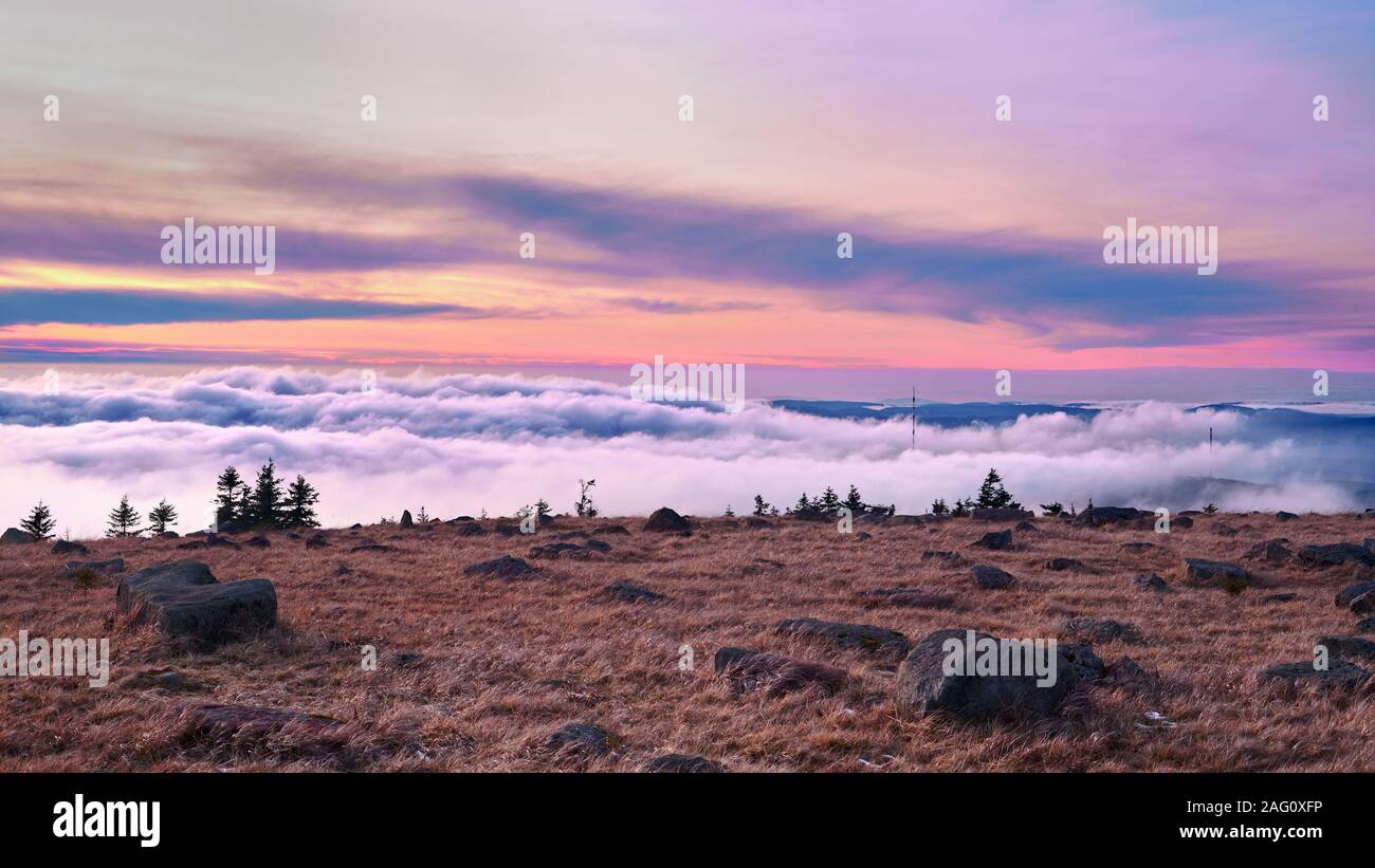On the mountain top at sunset over a sea of clouds. A sky in beautiful colors, Mount Brocken, Harz mountain range, Saxony-Anhalt, Germany. Stock Photo