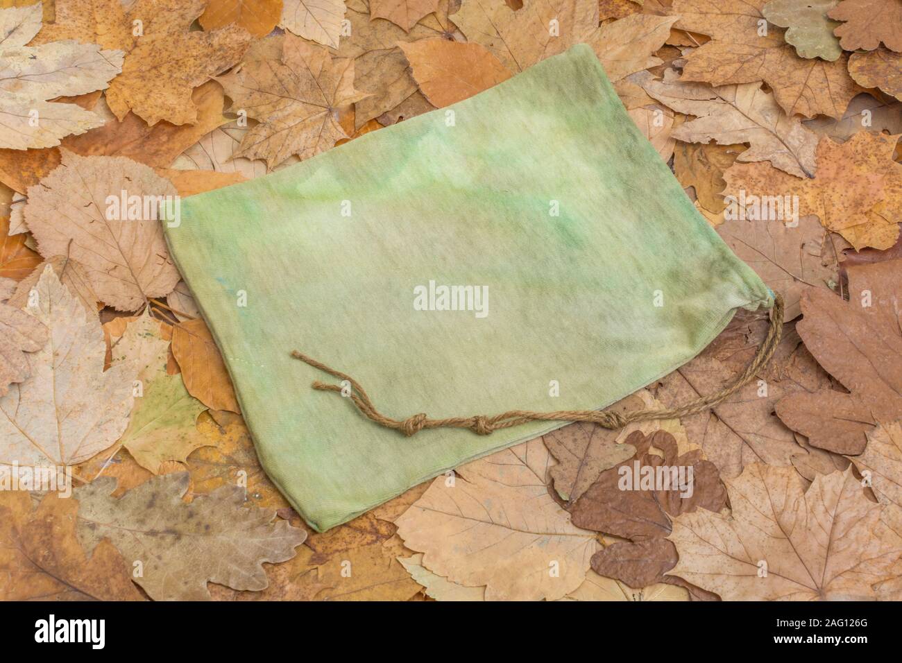 Small rustic possibles bag / ditty bag on floor of autumnal leaves. Metaphor survival skills, survival knowledge, bushcraft. Stock Photo