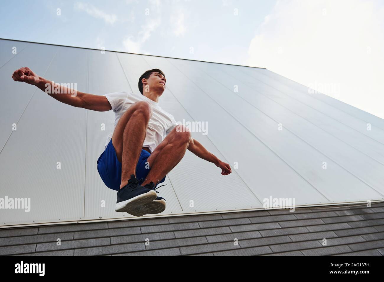 Into the air. Young sports man doing parkour in the city at sunny daytime Stock Photo
