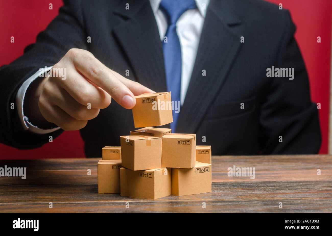 A businessman is building a stack of cardboard boxes. Business management, problem solving support. Production of goods and products, welfare. Distrib Stock Photo