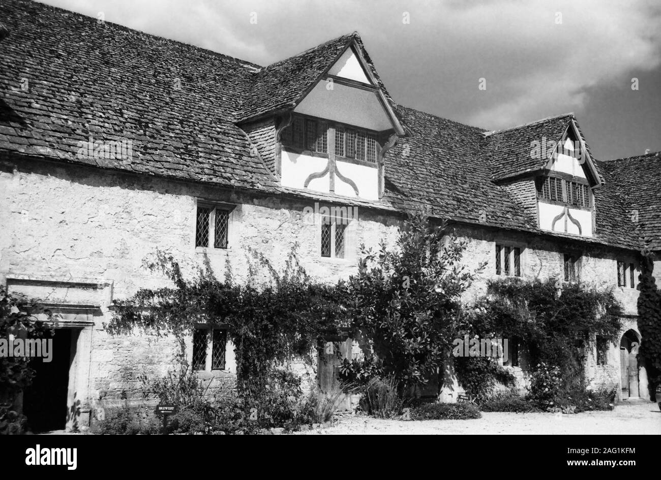 Lacock Abbey, Lacock, Wiltshire, England, UK: the handsome16th-century stable courtyard has half-timbered gables, brewery and bakehouse.  Old black and white film photograph Stock Photo