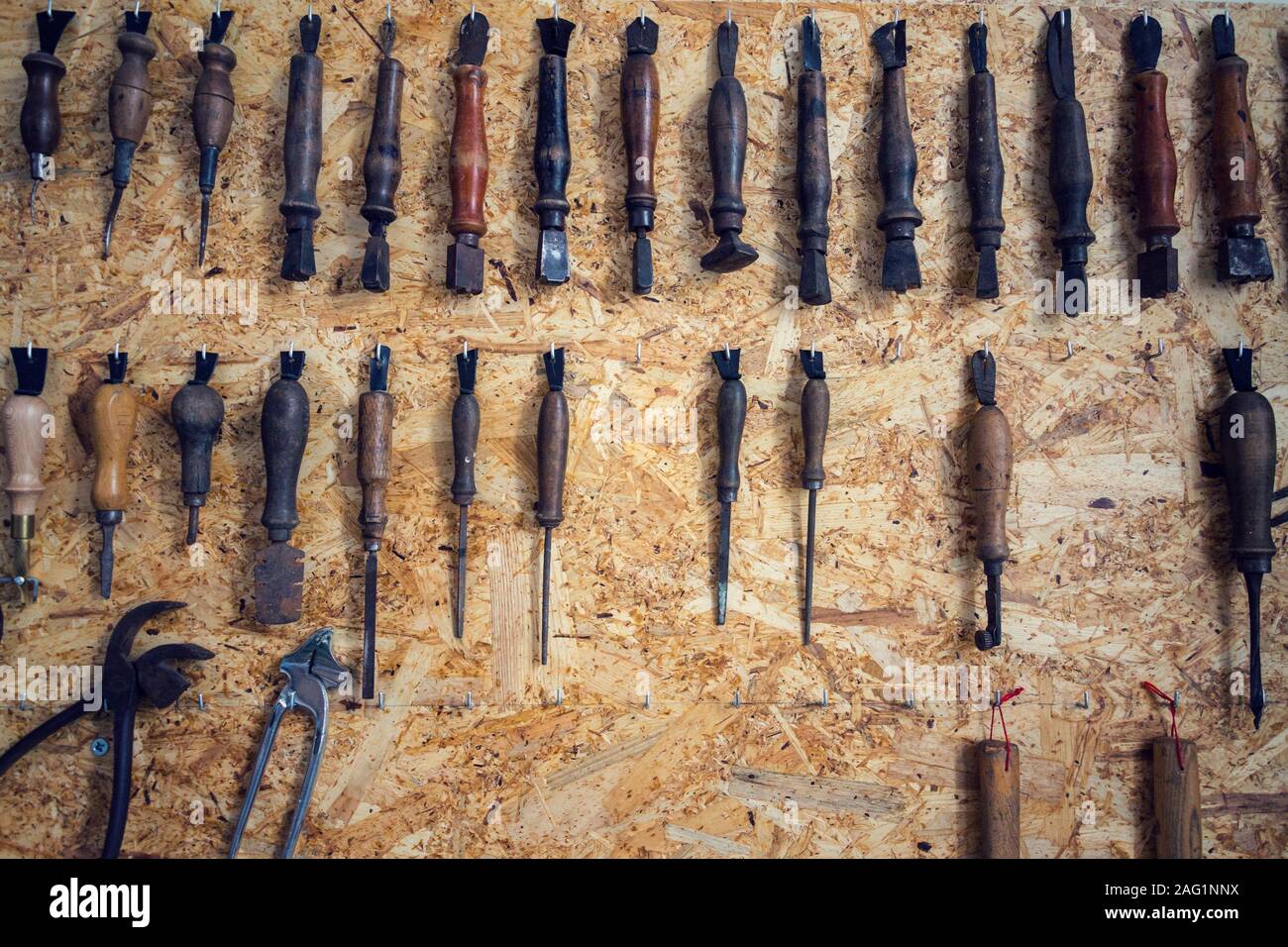 Group of old cobblers tools for handmade shoes production, awls and tongs for leather on wooden chipboard background, flat lay view Stock Photo