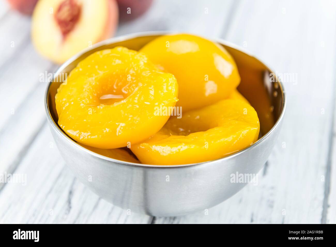 Canned Peaches (close-up shot) on vintage wooden background Stock Photo