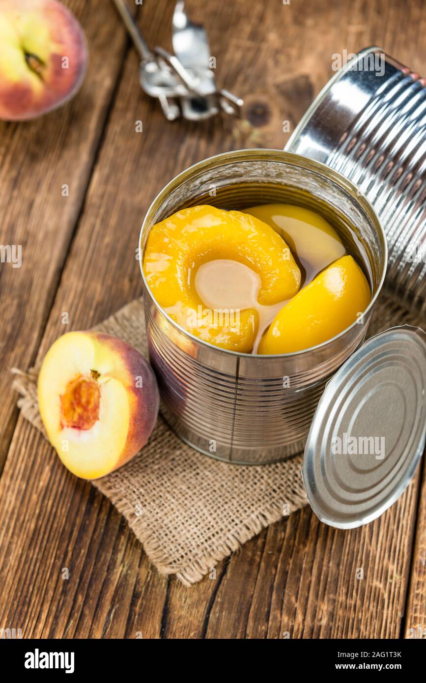 Canned Peaches (close-up shot) on vintage wooden background Stock Photo