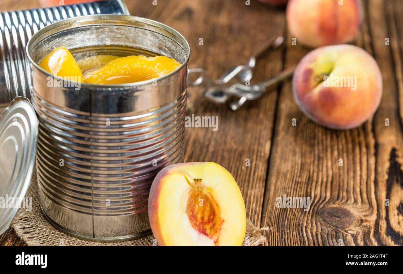 Portion of preserved Peaches (close-up shot) on wooden background Stock Photo