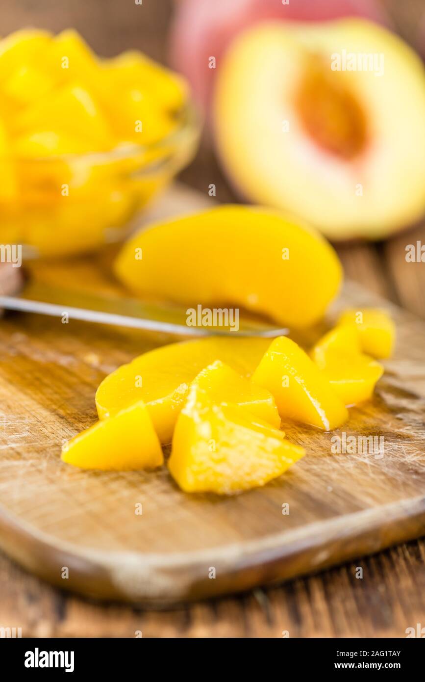Portion of preserved Peaches (close-up shot) on wooden background Stock Photo
