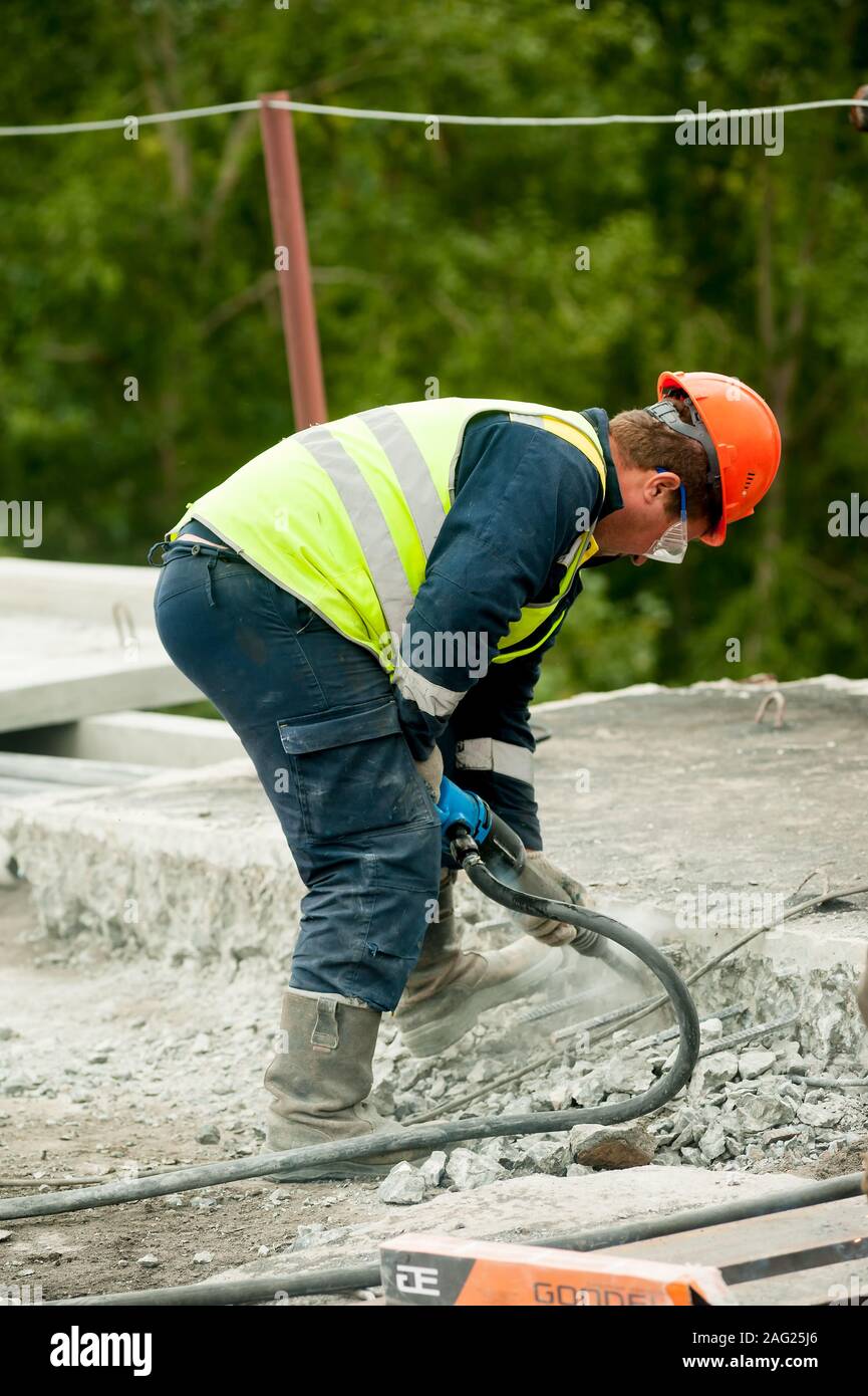 Worker drilling concrete at construction site Stock Photo