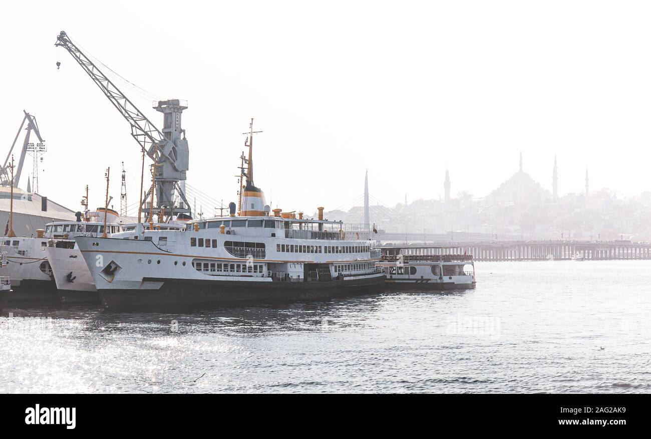 Shipyard and ferries, foggy Istanbul silhouette in the background Stock Photo
