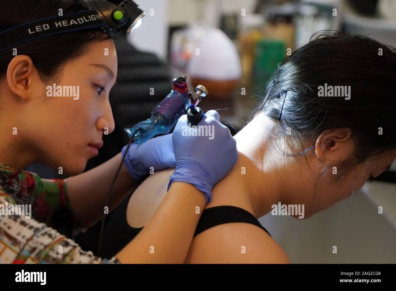 Middletown, CT / USA - December 7, 2019: Asian tattoo artist concentrates  while tracing a floral tattoo design on the back of the client's neck Stock  Photo - Alamy