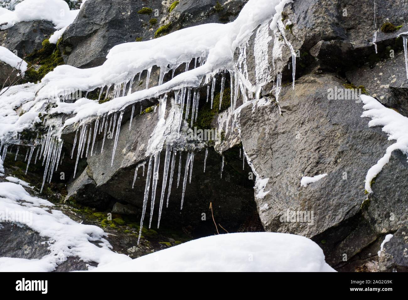 Horizontal close-up of icicles on rock near a waterfall. Stock Photo