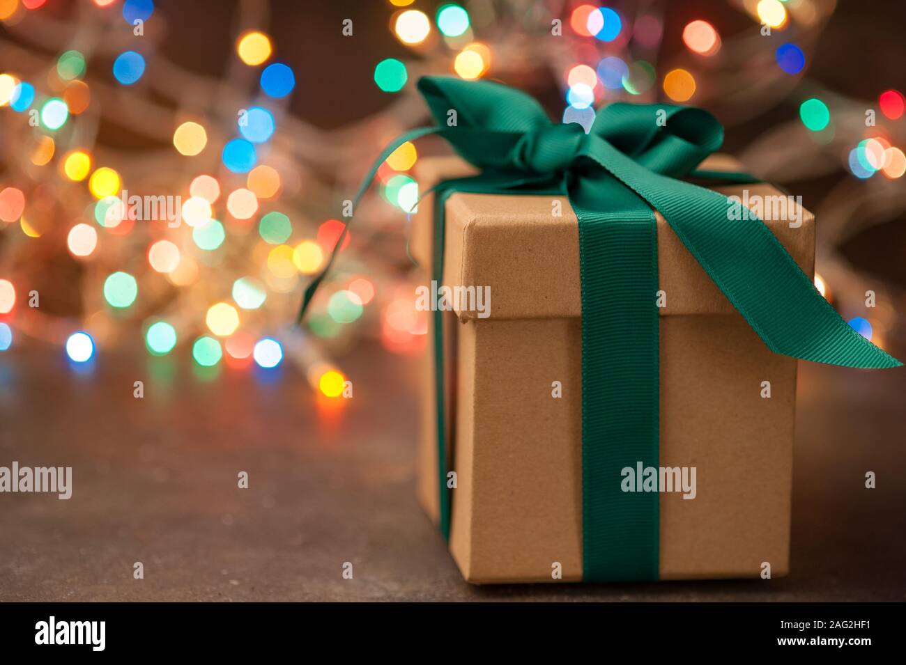 Kraft box with a gift on the background of the Christmas lights. Bokeh in the background Stock Photo