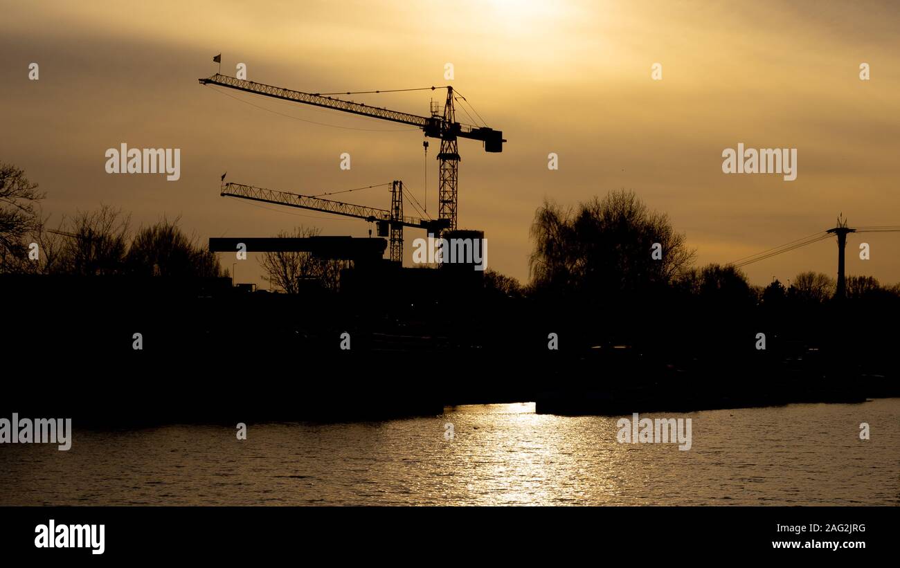 Two cranes in the sunset, in the front the river port Mühlheim, Cologne, Germany Stock Photo