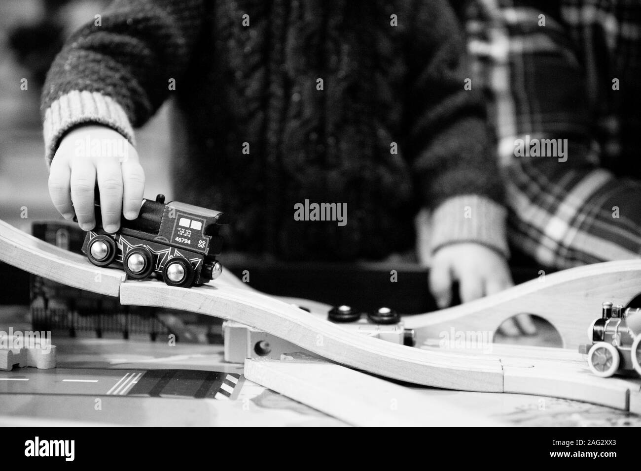 Closeup shot of a child playing with a train toy in black and white Stock Photo