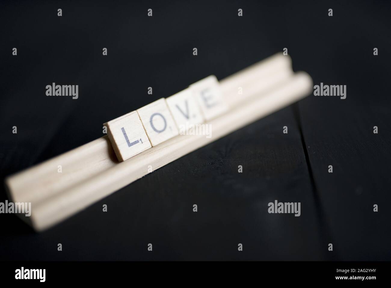 Closeup shot of wooden block spelling love on a black wooden surface Stock Photo
