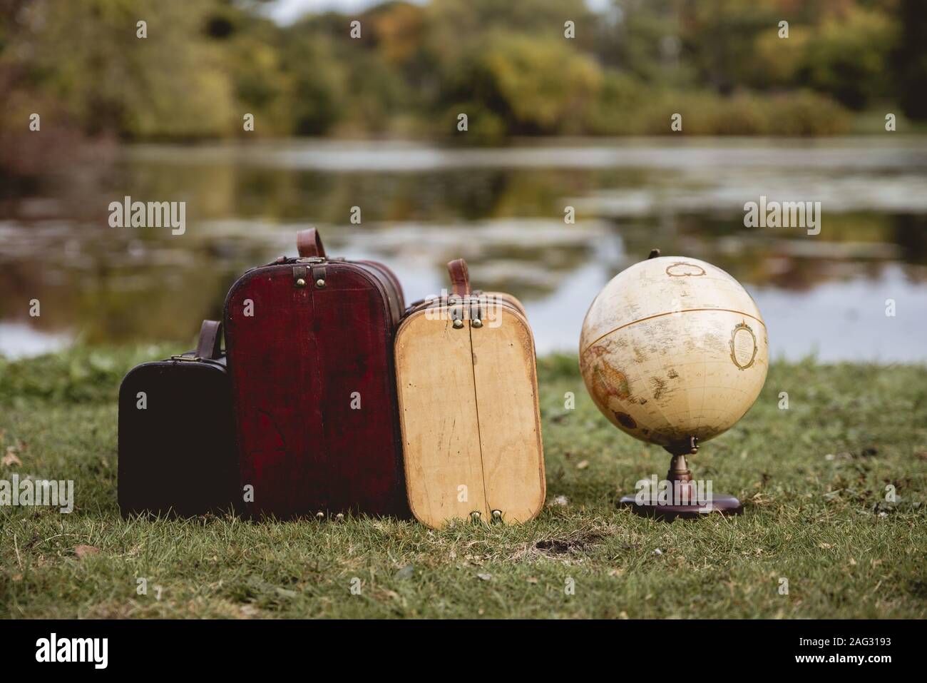 Closeup shot of old suitcases on a grassy field near a desk globe with a blurred background Stock Photo