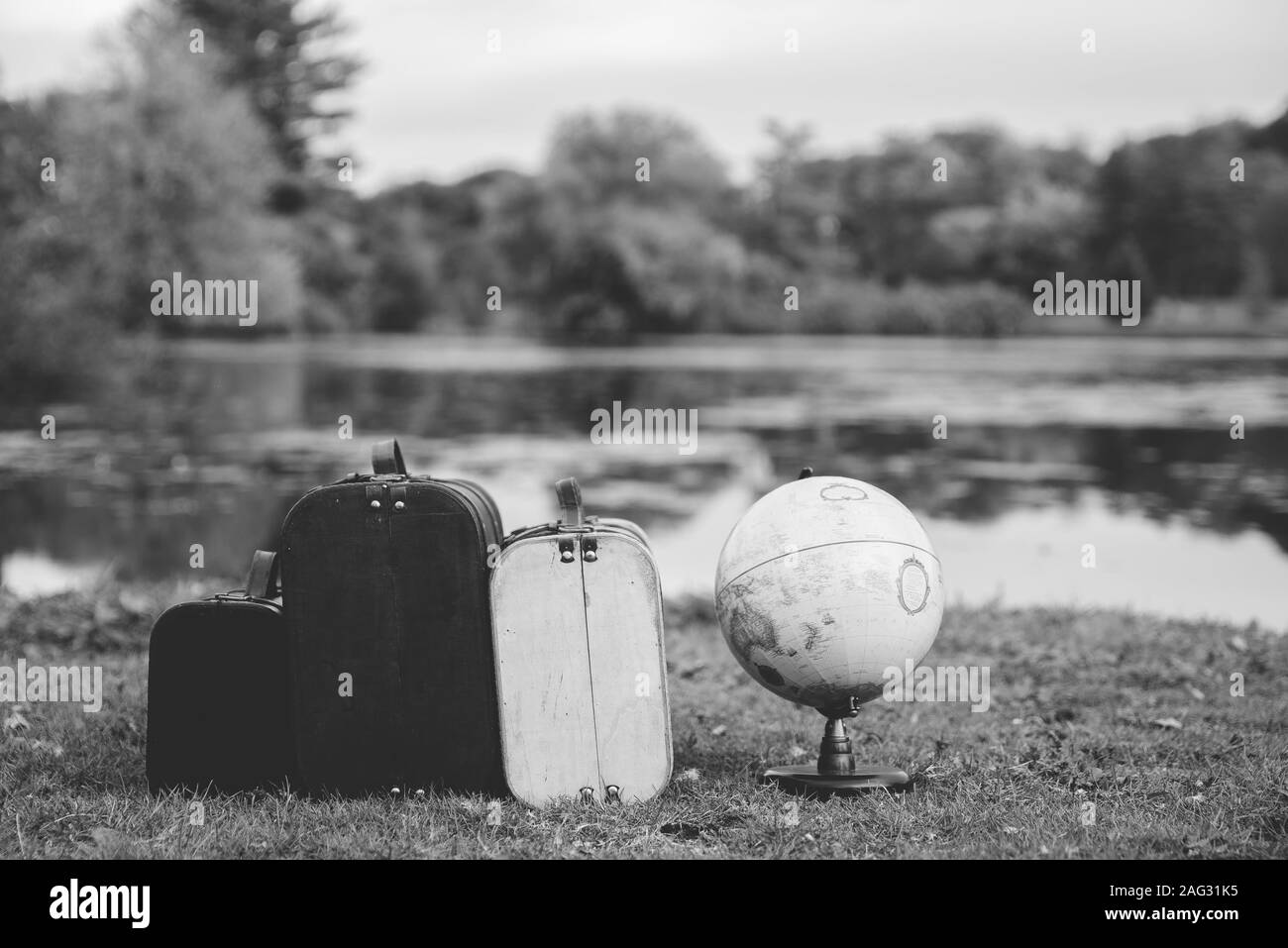 Closeup shot of old suitcases near a desk globe in a grassy field with a blurred background Stock Photo