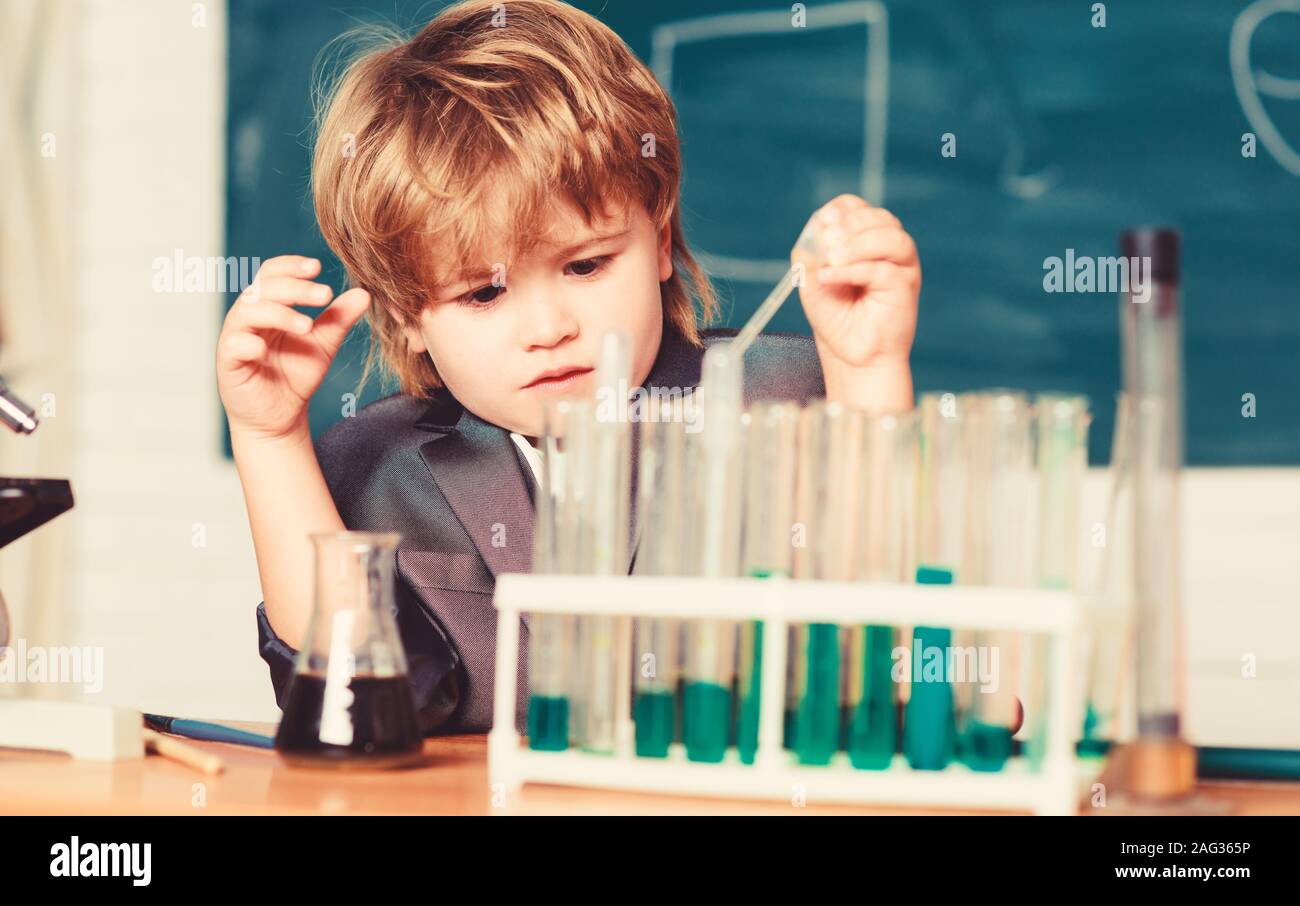 Wunderkind experimenting with chemistry. Boy use microscope test tubes ...