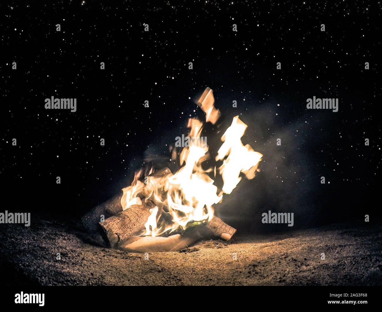 Horizontal shot of a bonfire at night time under the beautiful starry ...