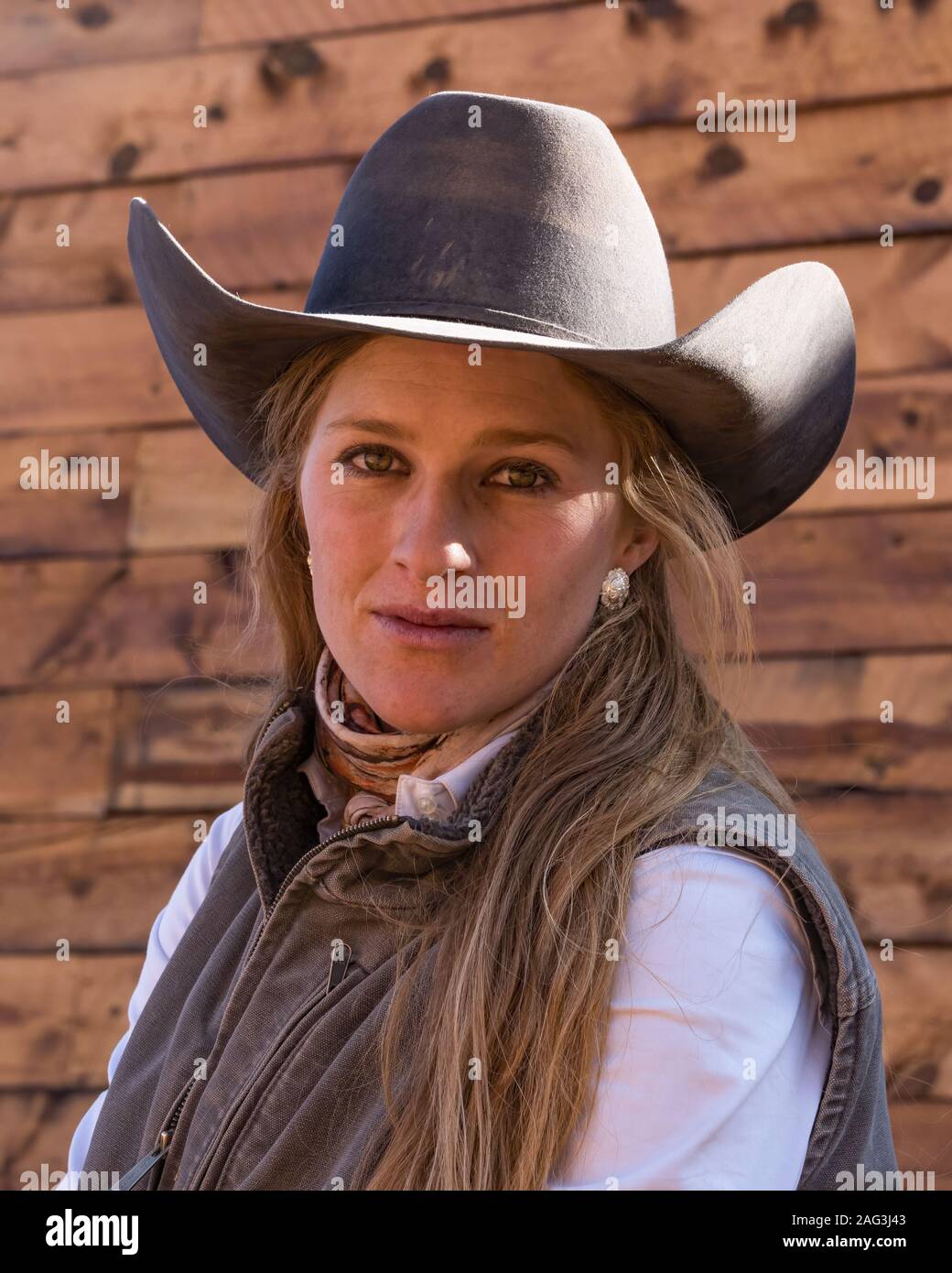 A young attractive working cowgirl wrangler poses on her horse on a ranch near Moab, Utah. Stock Photo