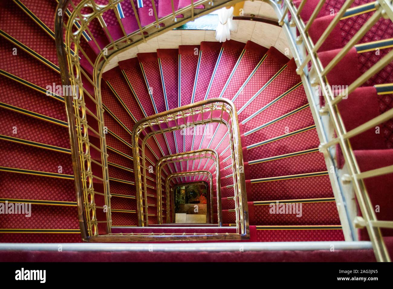 High angle shot of a pink spiral staircase with golden handles in a beautiful building Stock Photo