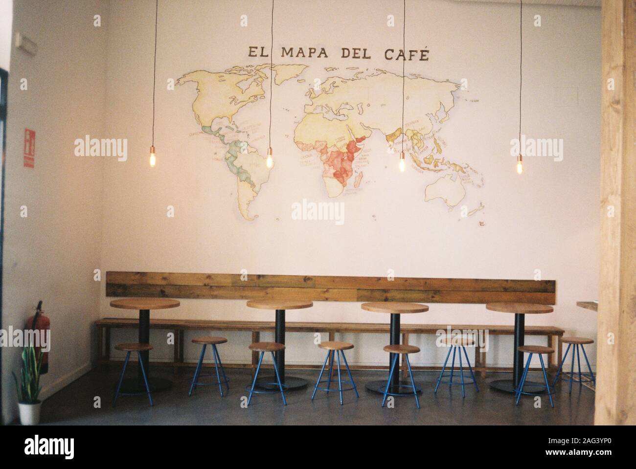 Inside shot of a cafe with round tables and chairs near a map of coffee print on the wall Stock Photo