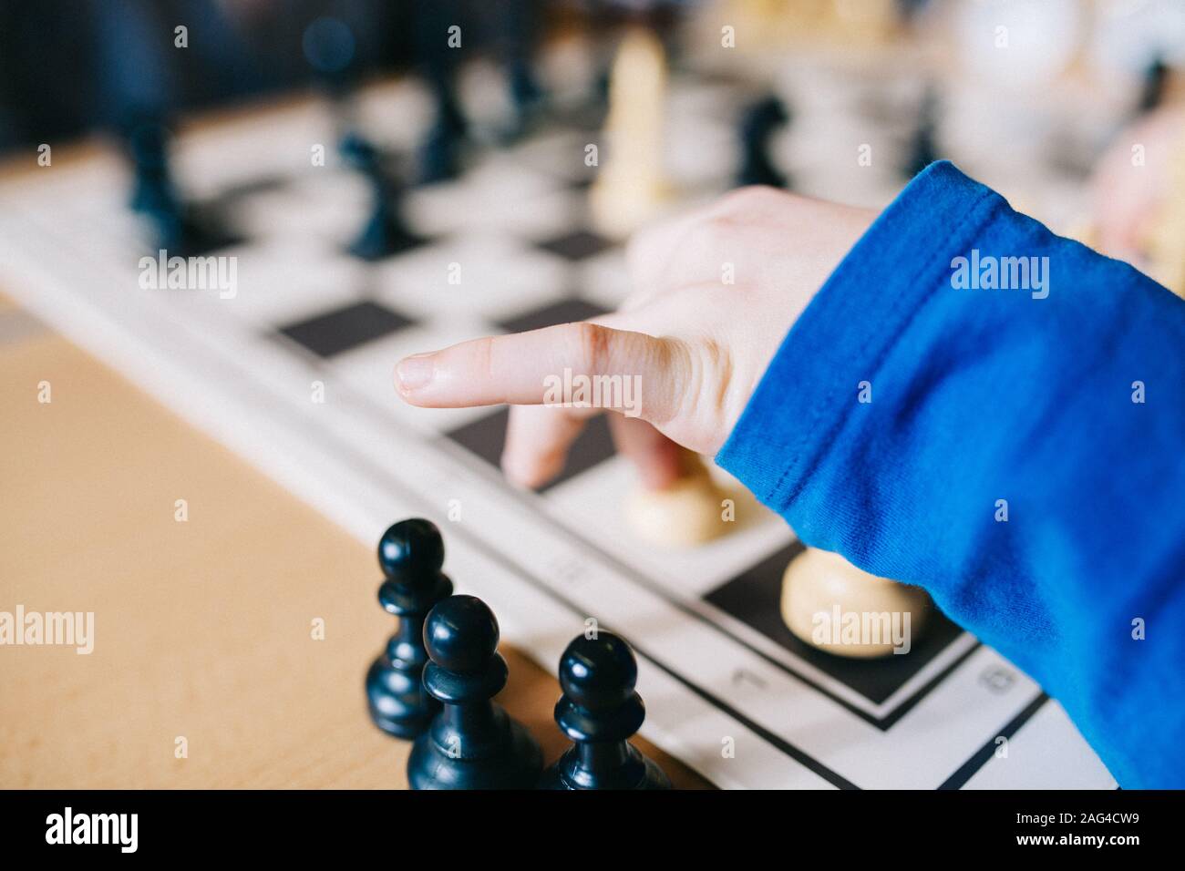 Closeup shot of a human arm in a blue blouse moving chess figures on a chess desk Stock Photo