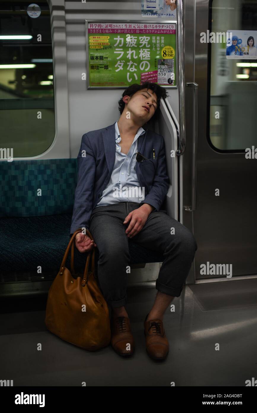 Young man sleeping in subway, Tokyo, Japan Stock Photo