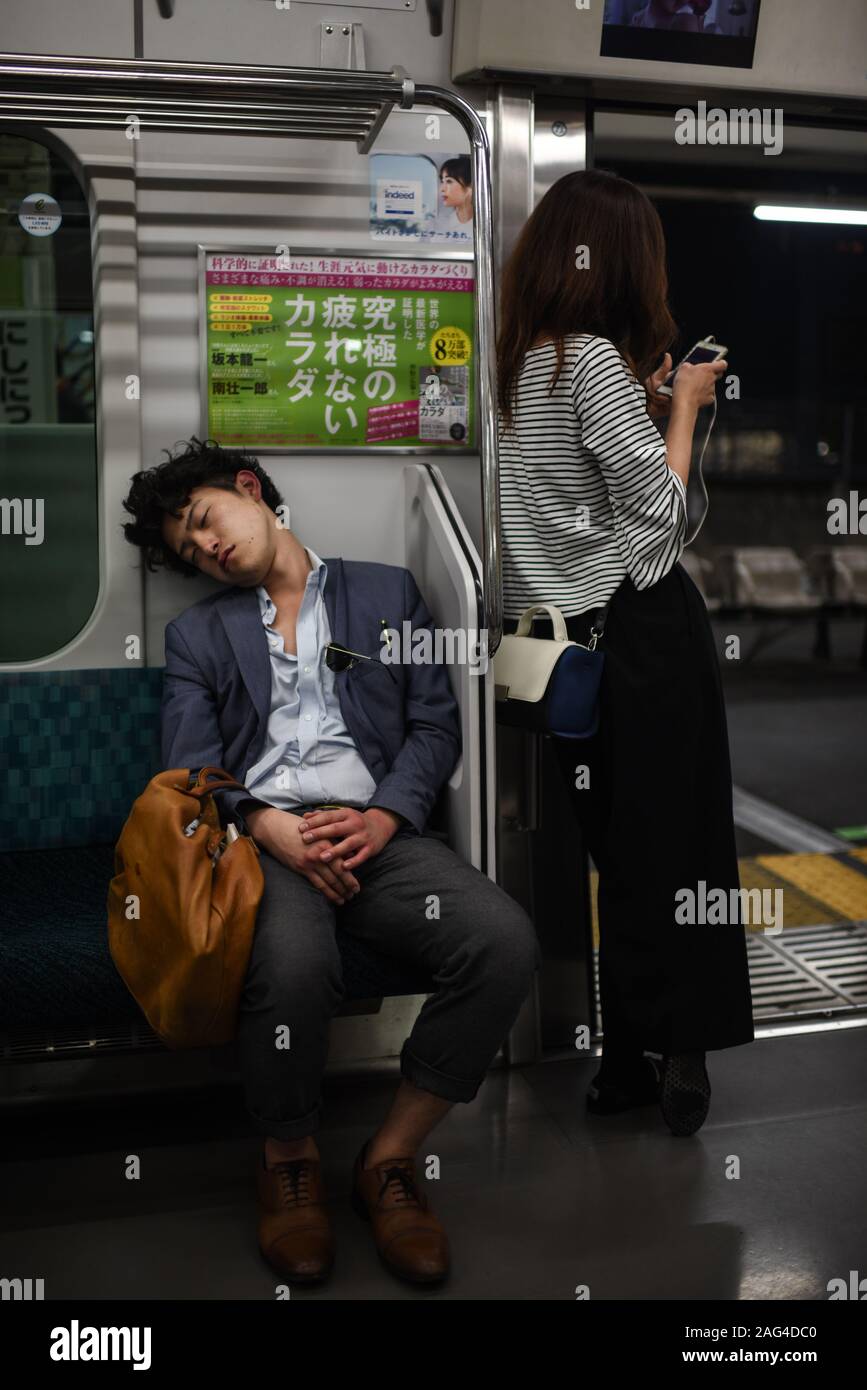 Young man sleeping in subway, Tokyo, Japan Stock Photo