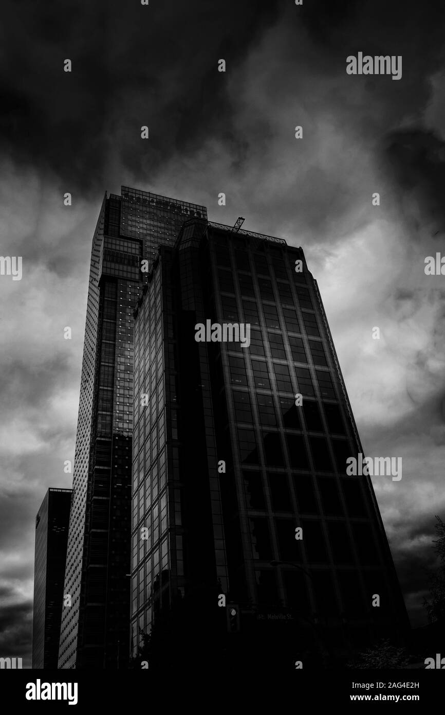 Vertical low angle greyscale shot of tower block with mirror windows