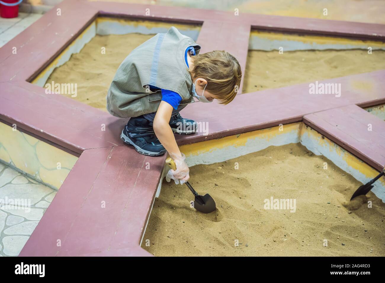 Happy boy using shovel finding hidden artifact under the ground Stock Photo