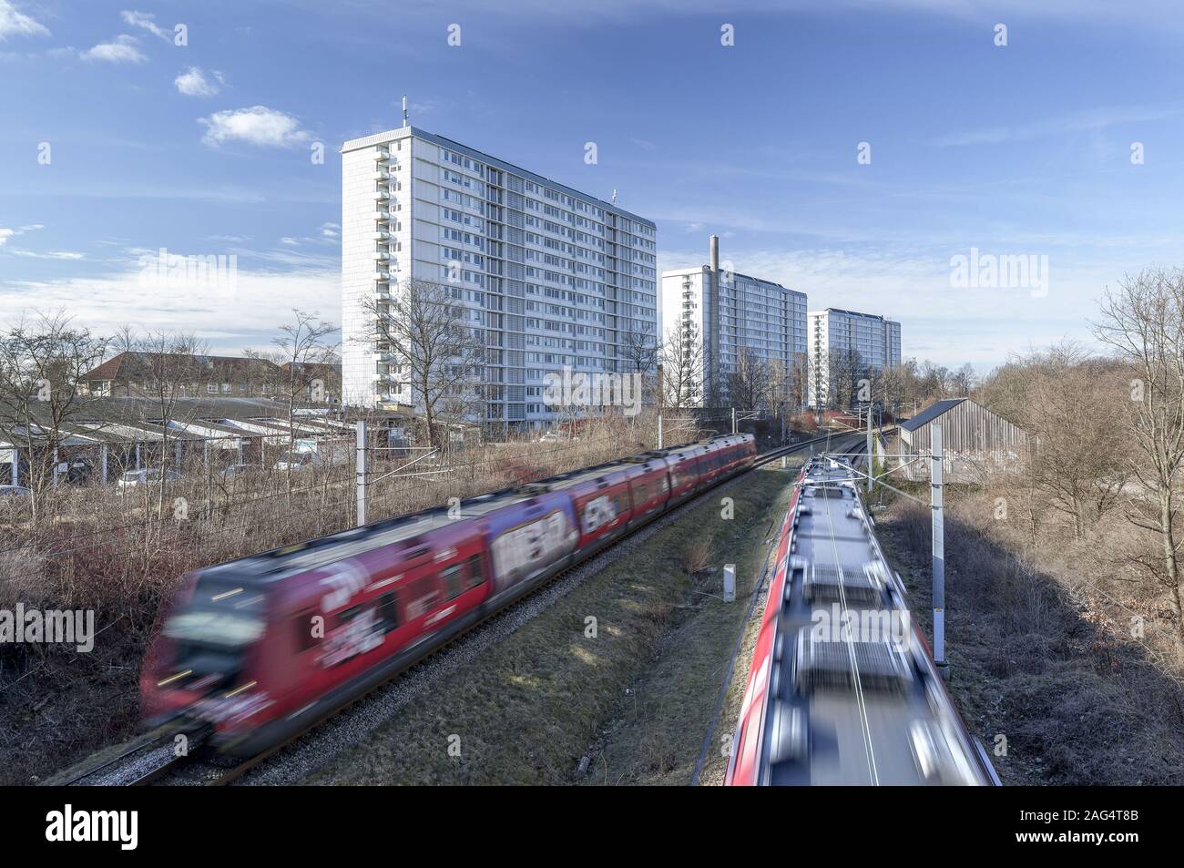 Moving trains crossing three big white buildings Stock Photo - Alamy