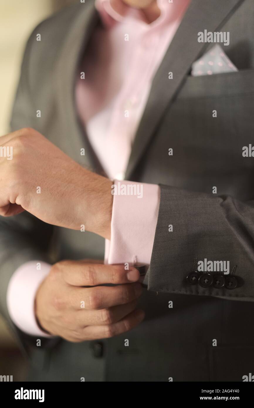 pink shirt and grey suit buttoning 