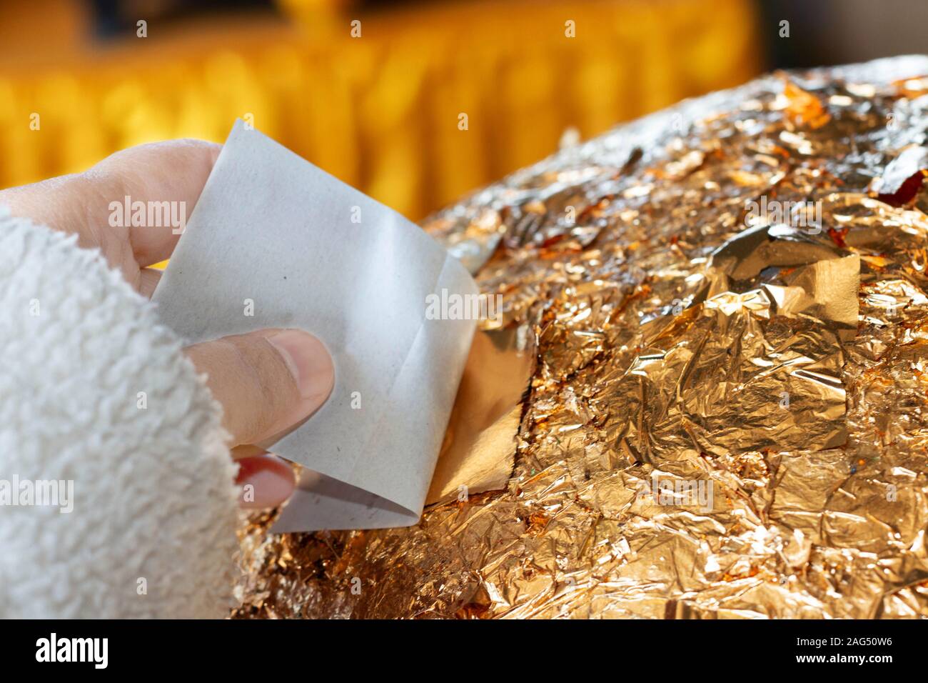 hand of buddhist gilding gold leaflet on golden ball in temple to worship buddha Stock Photo