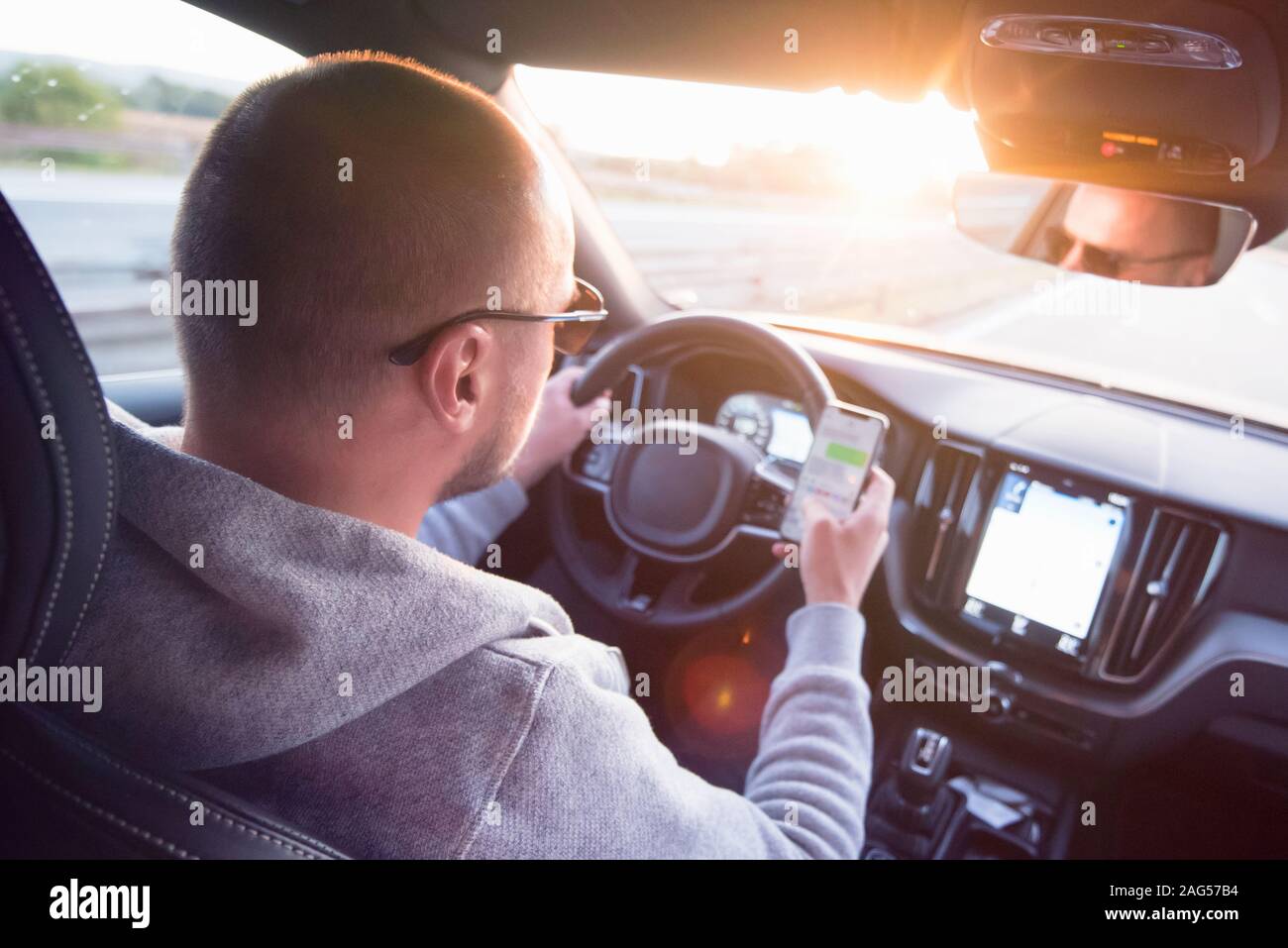 Man looking at mobile phone while driving a car. Stock Photo