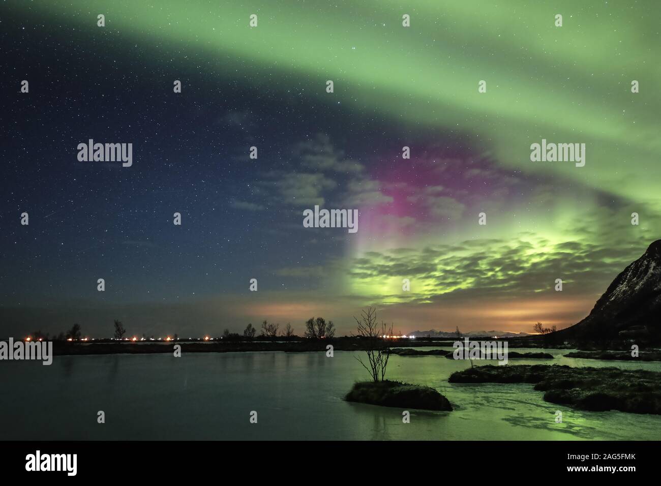 Reflection of the amazing northern lights in the water surrounded by ...