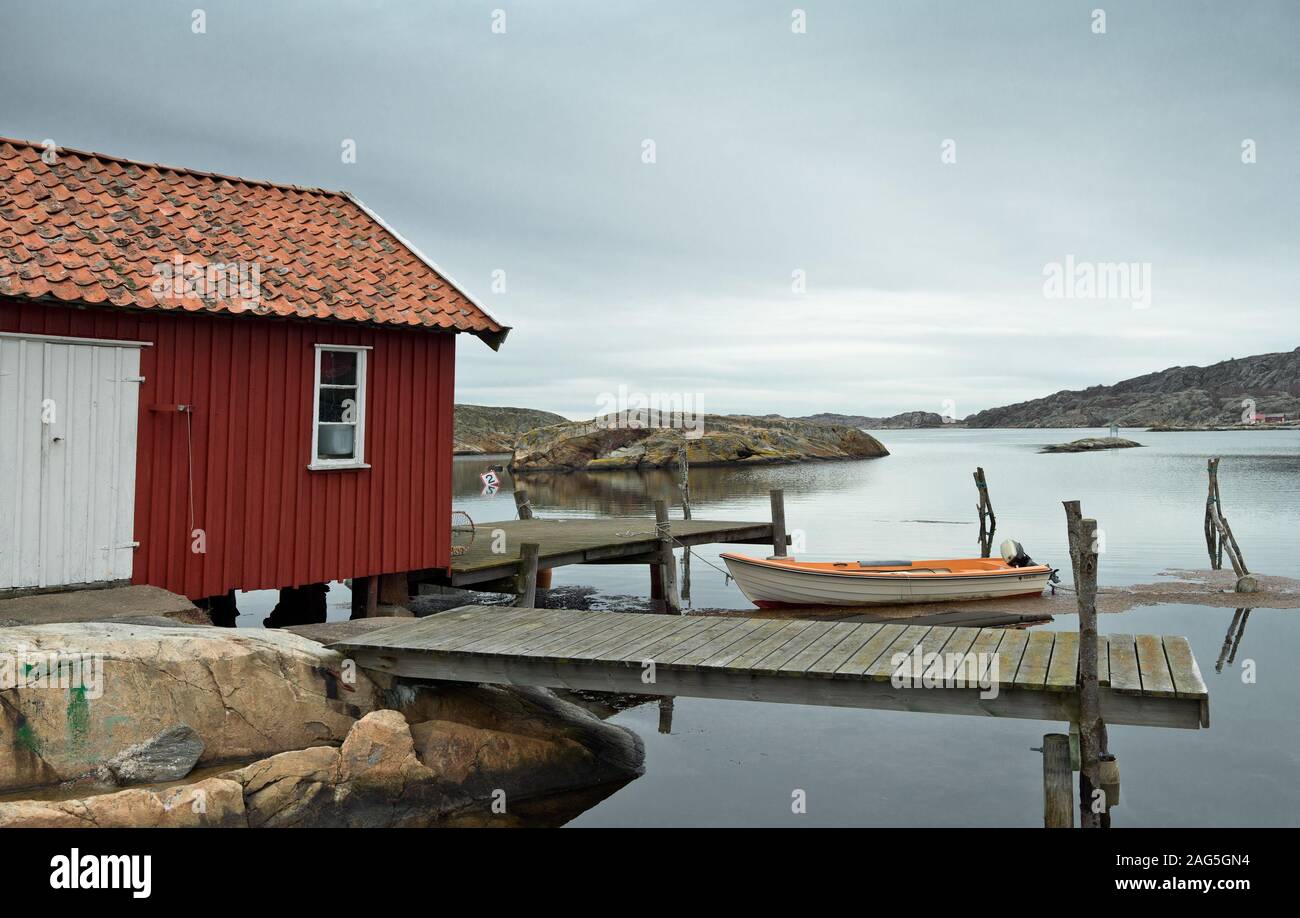 A Red Cabin On A Wooden Pier And A Boat In The Middle Of A Lake