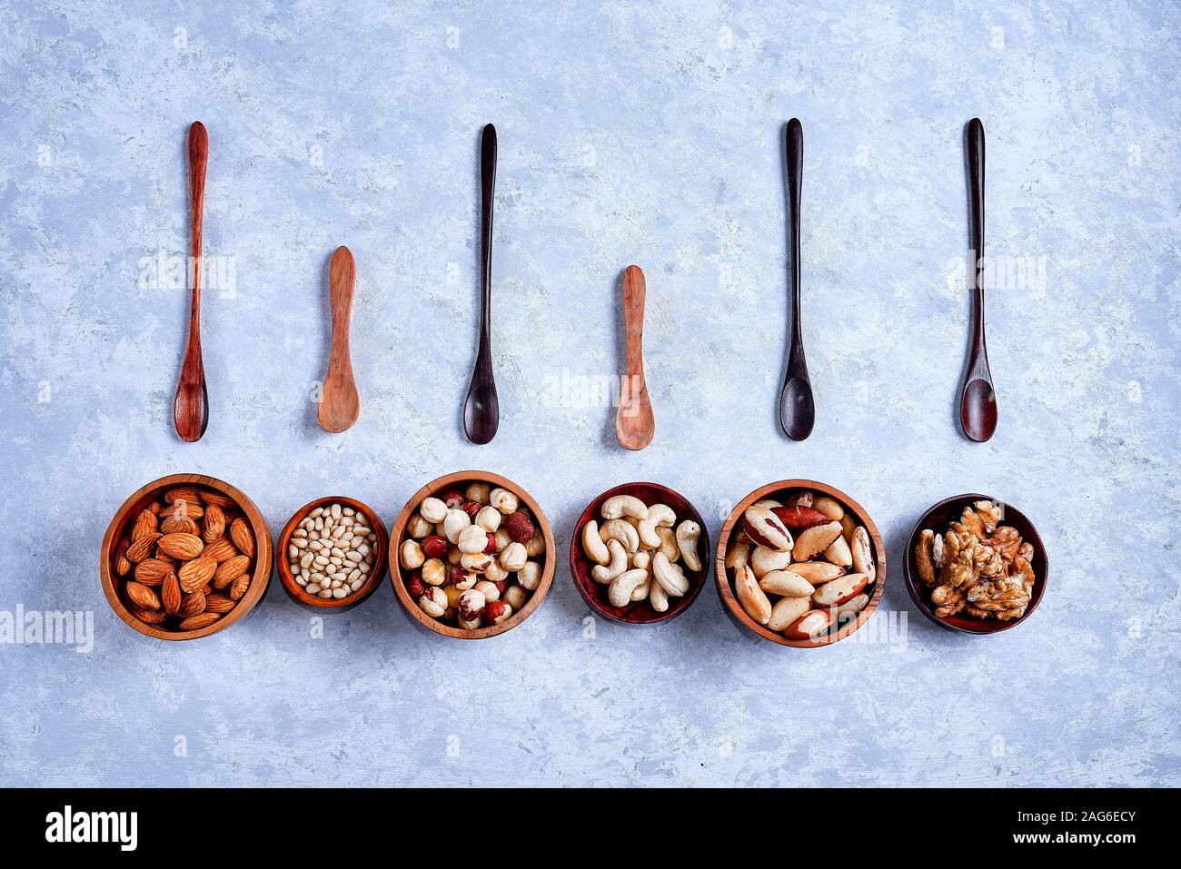 a variety of nuts in wooden bowls pattern on a blue background Stock Photo