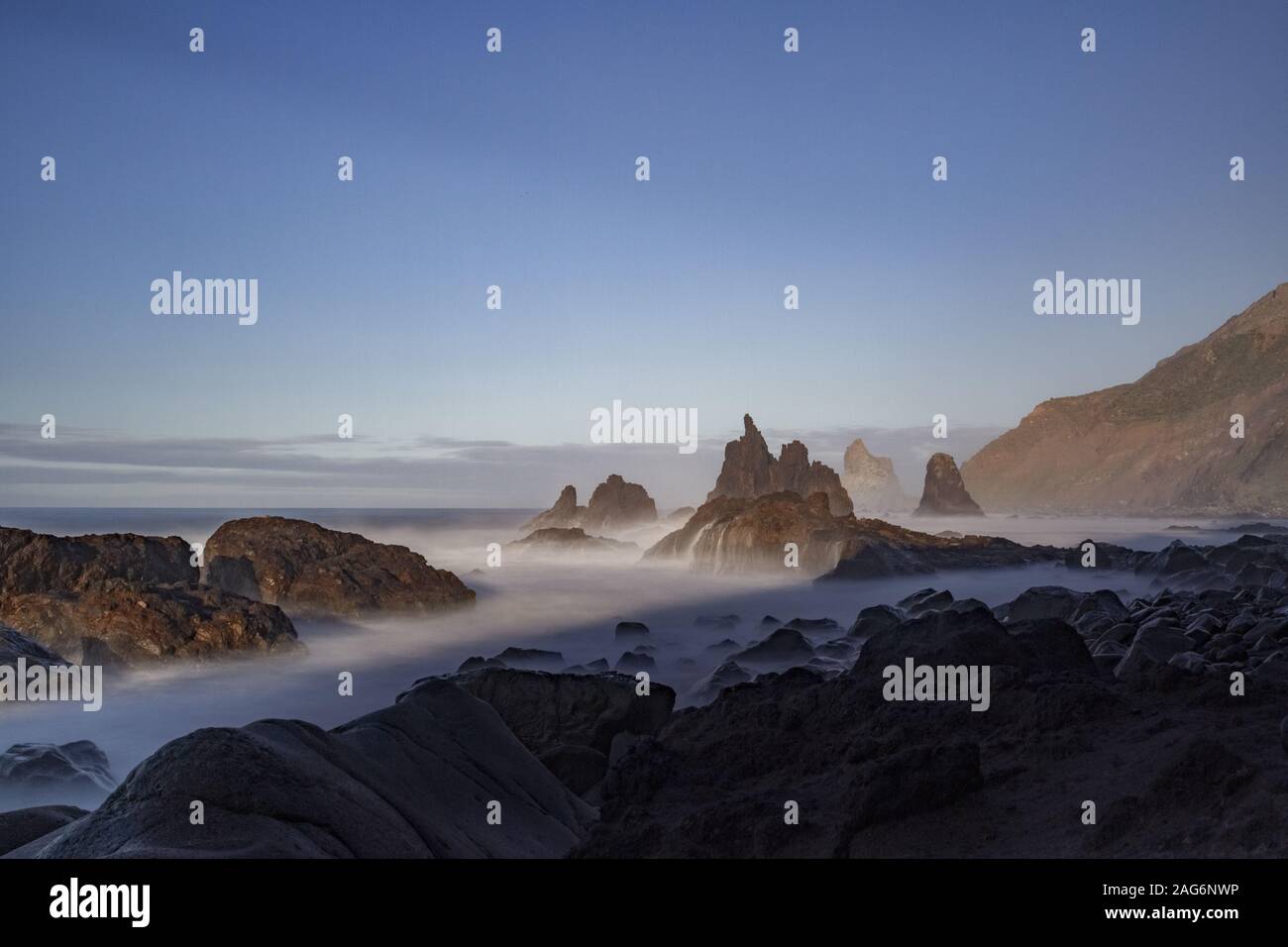 Breathtaking view of the mountains tops under the blue sky captured in a foggy weather Stock Photo