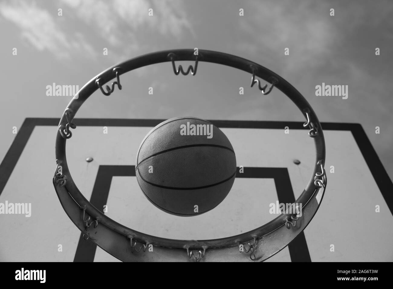 Low angle shot of a basketball in a basketball hoop under the dark sky Stock Photo