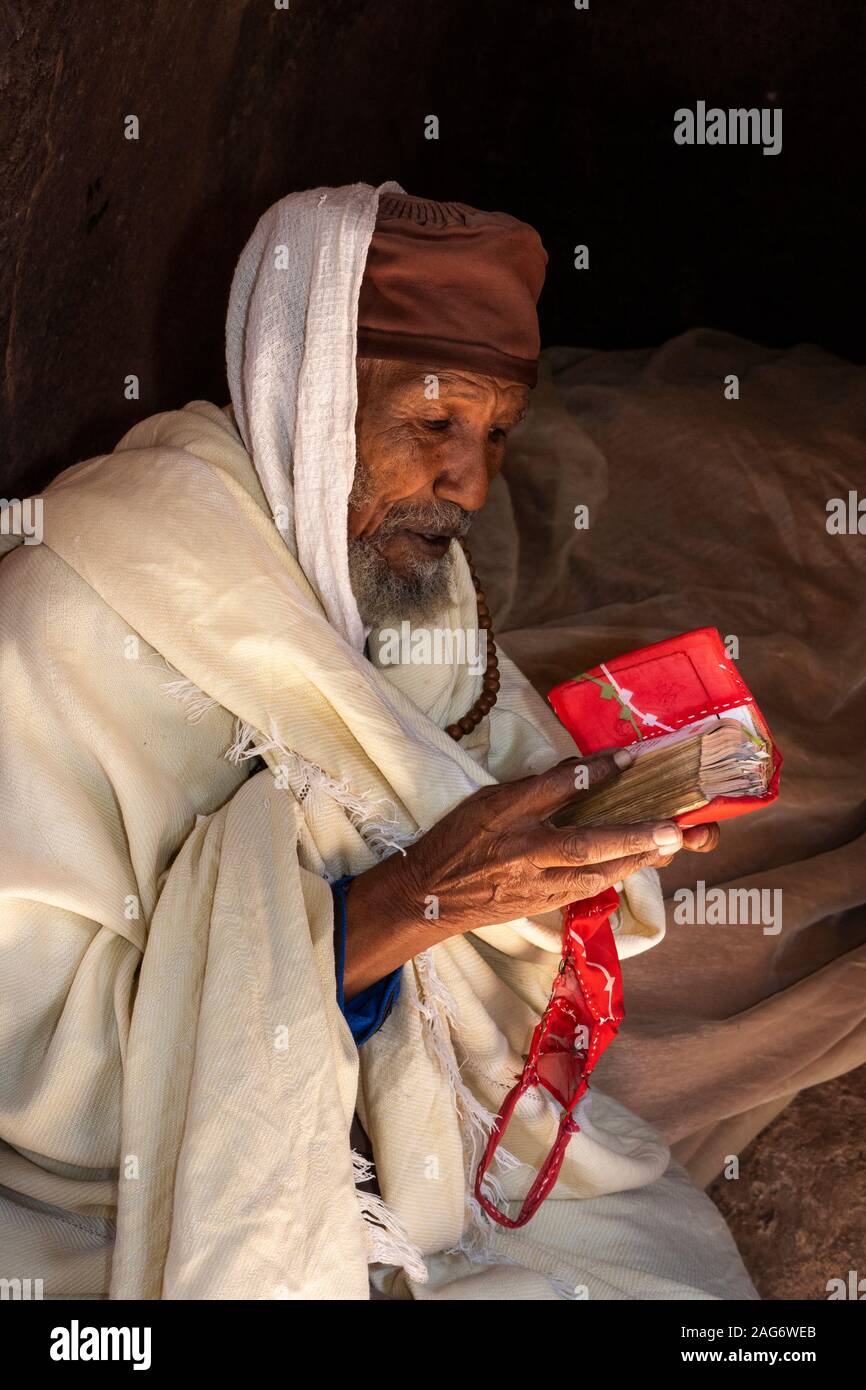 Ethiopia, Amhara Region, Lalibela, Bet Maryam Church, devotee reading gospel in Amharic text Stock Photo
