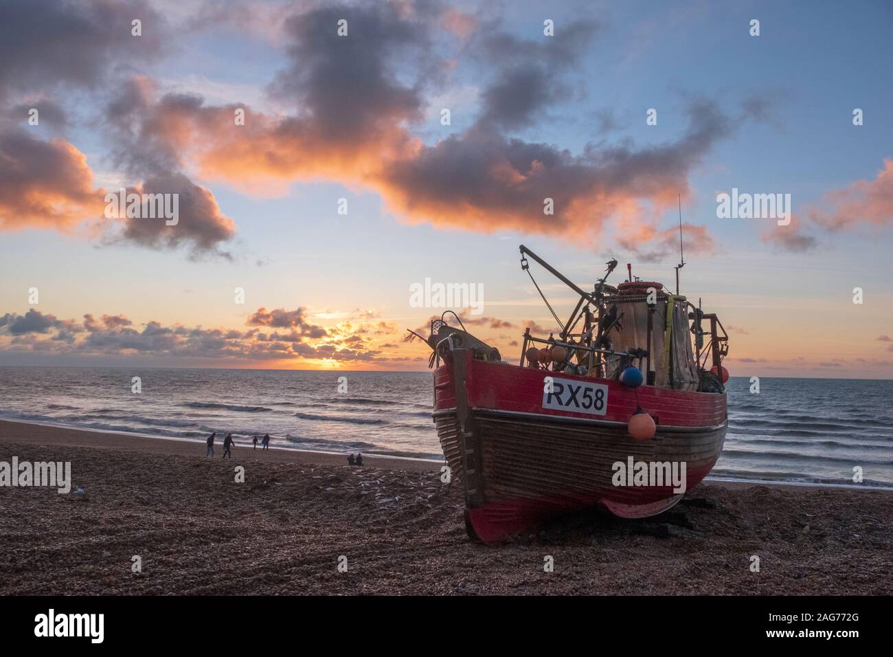 Hastings, East Sussex, UK. 18th December 2019. Colourful sunrise on the stade for people walking on the beach on a sunny day in Hastings. Carolyn Clarke/Alamy Live News Stock Photo