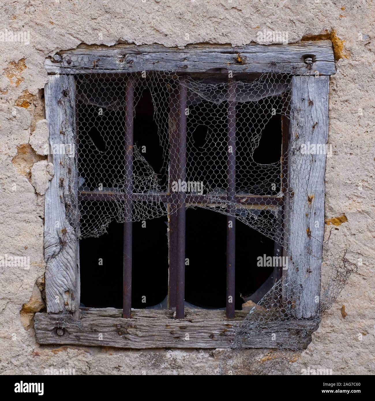 Closeup shot of an old broken window covered in net with holes Stock Photo