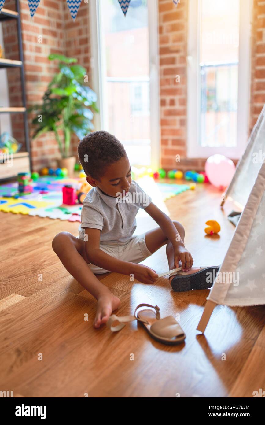 Beautiful african american toddler putting on shoes outside tipi at