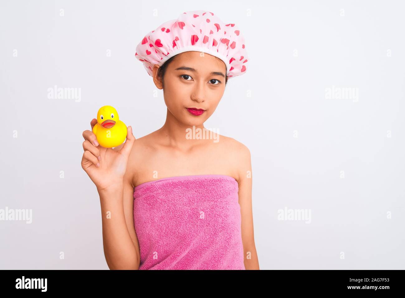 Chinese woman wearing shower towel and cap holding duck toy over ...