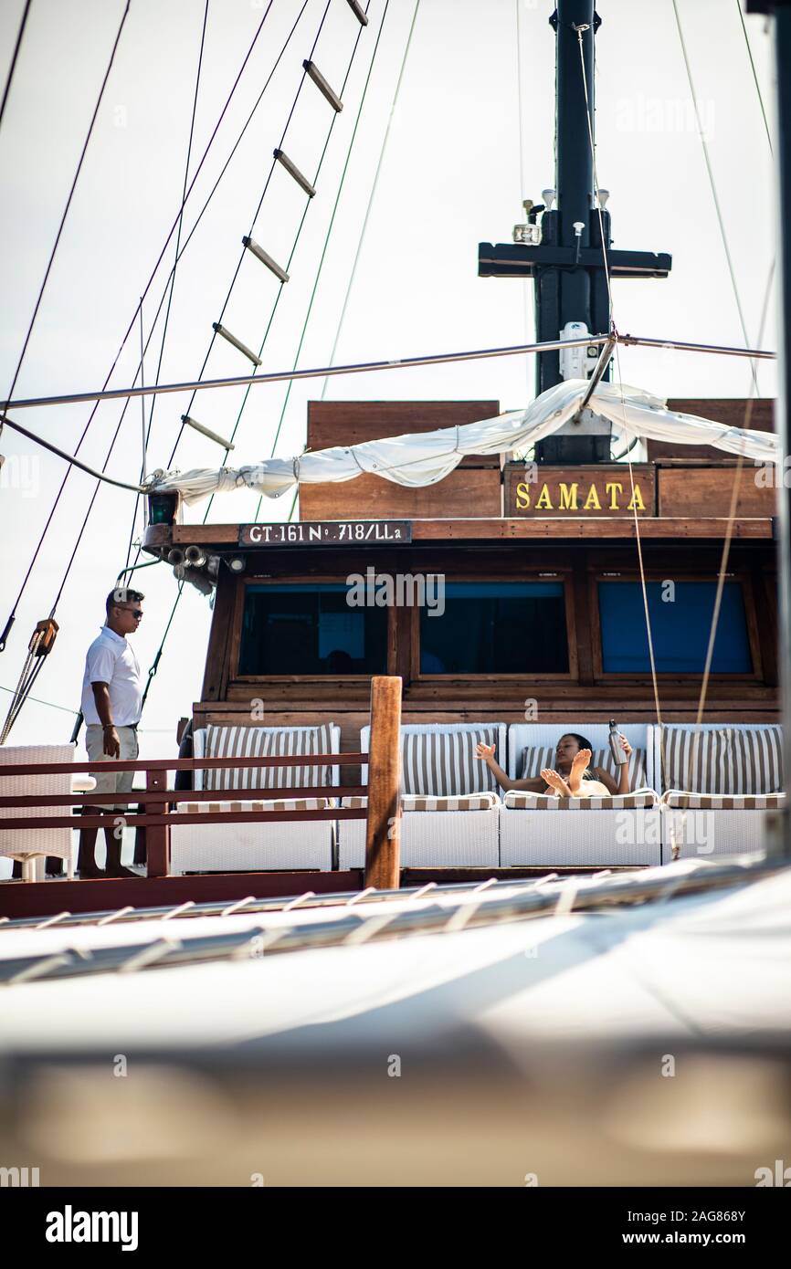 Samata Luxury Liveaboard phinisi boat guest laying down served by staff member Stock Photo