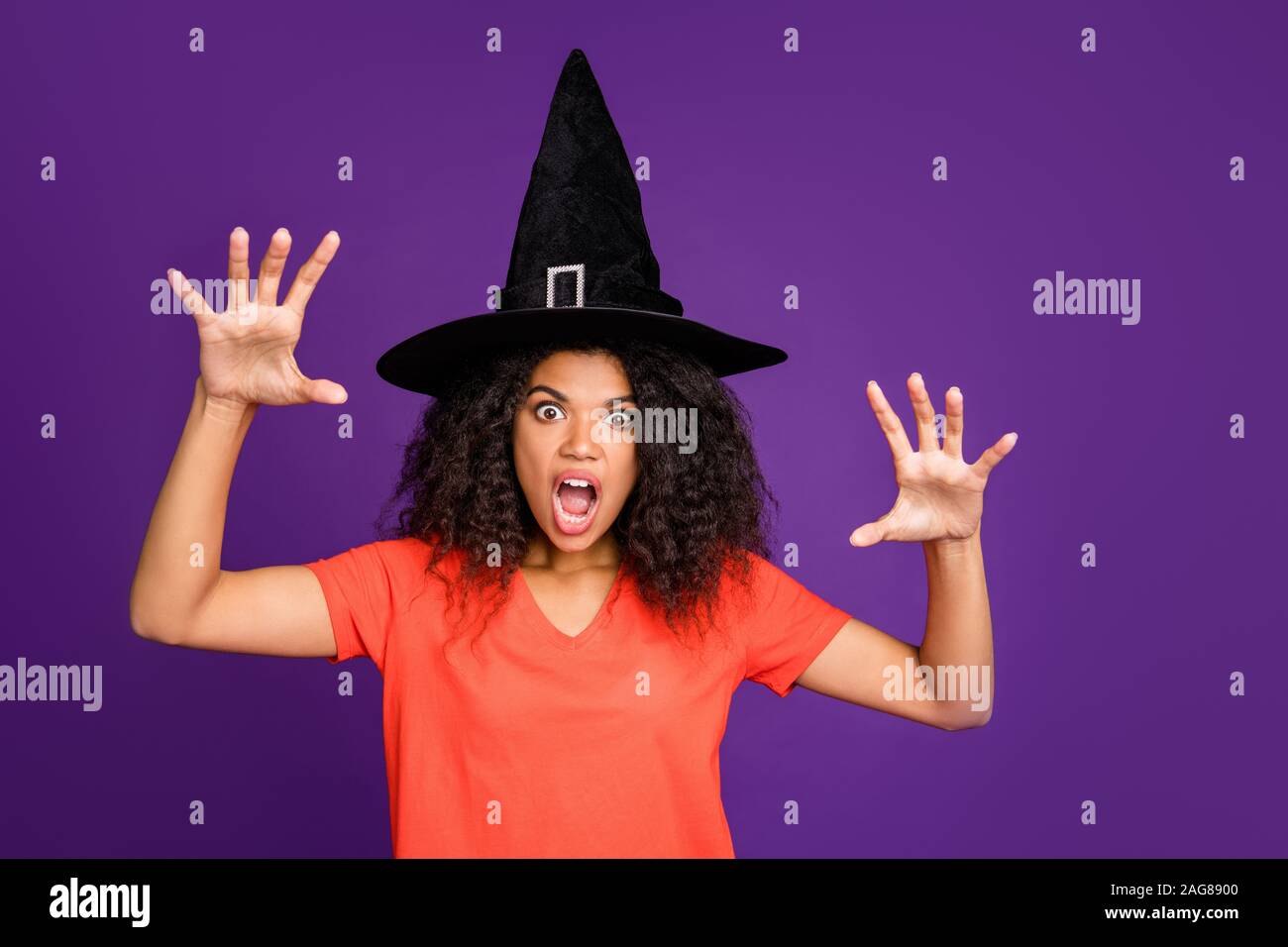 Photo of scary terrible spooky frightful warlock wearing conical cap casting spell to curse you with horrifying facial expression in orange t-shirt Stock Photo